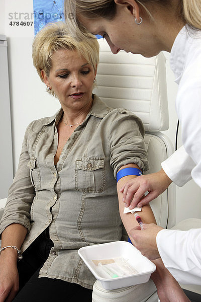 Arztpraxis  Blutabnahme zur Blutuntersuchung im Labor bei einer Patientin durch eine Praxishhilfe  medizinisch-technische Angestellte