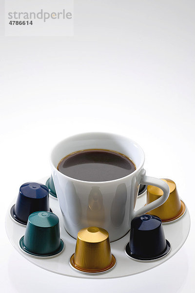 Tasse mit frisch gebrühtem Kaffee und Kaffeekapseln