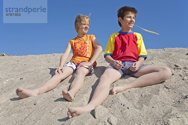 Zwei Jungen sitzen im Sand  Strand von Timmendorf auf der Insel Poel  Mecklenburg-Vorpommern  Norddeutschland  Deutschland  Europa