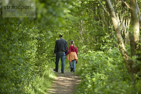 Ein Mann geht mit einem kleinen Mädchen in den Wald