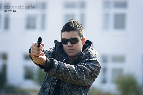 Teenager mit Softair Pistole auf einem Schulhof  gestellte Szene