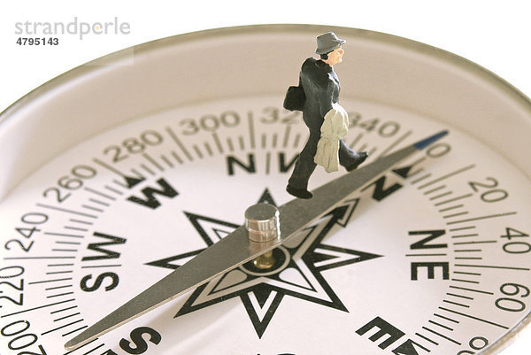 Businessmann Figur läuft auf Kompass Richung Norden  Symbolbild für auf richtigem Kurs sein