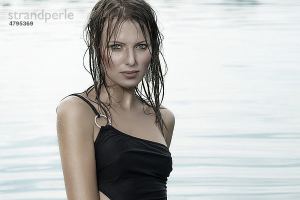 Junge Frau in einem schwarzen Badeanzug und mit nassen Haaren beim Baden in einem See