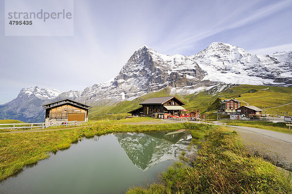 Der Eiger spiegelt sich in einem Bergsee  dahinter ein Bergrestaurant und die Passhöhe Kleine Scheidegg  Kanton Bern  Schweiz  Europa
