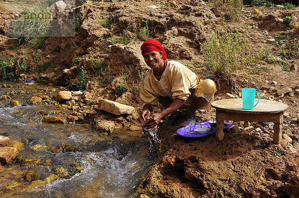 Eine ältere Berber-Frau reinigt an einem Bach ihr Geschirr  Mittlerer Atlas  Marokko  Afrika