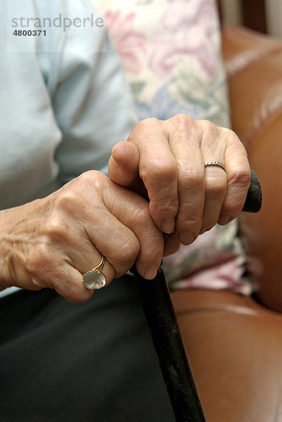 Hände einer älteren Frau mit einem Spazierstock
