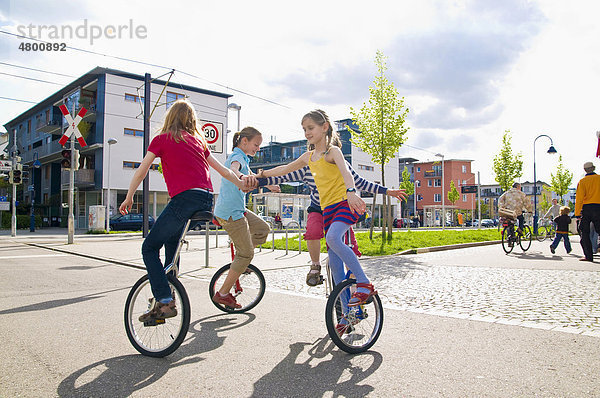 Auf Einrad fahrende Kinder in einer Spielstraße im Vauban-Viertel in Freiburg im Breisgau  Baden-Württemburg  Deutschland  Europa