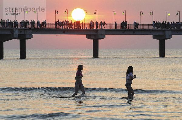 Seebrücke beim Sonnenuntergang mit badenden Mädchen  Miedzyzdroje  Polen  Europa