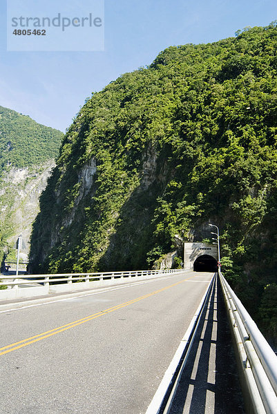 Straße und Tunnel durch einen grünen Berg