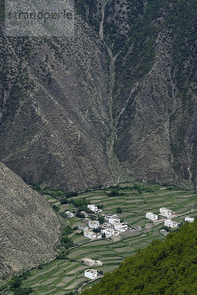 Blick von oben auf die tibetische Architektur eines kleinen Dorfes  Häuser inmitten eines steilen Canyons mit Feldterrassen zum Anbau  Xiangcheng  Chaktreng  Kham  Sichuan  China  Asien