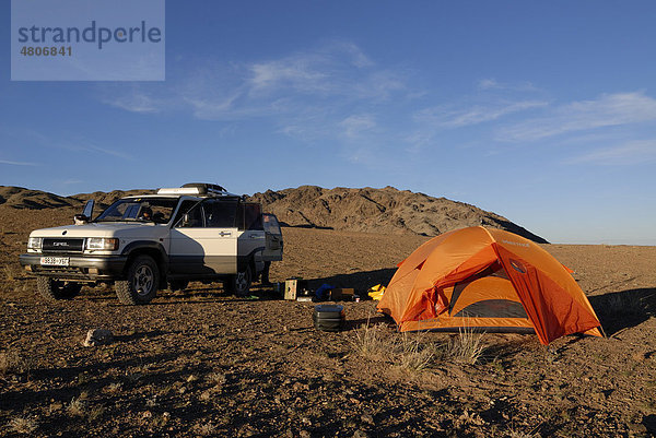 Weißer Opel Landcruiser steht mit offenen Türen neben Zeltlager mit Trekkingzelt und Outdoor Equipment in der Wüste Gobi  Khorgoryn Els  Gurvan Saikhan Nationalpark  Ömnögov Aimak  Mongolei  Asien