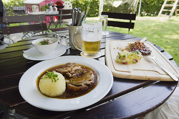 Schweinebraten mit Kartoffelknödel und Bier im Biergarten  bayerisches Essen  Bayern  Deutschland  Europa