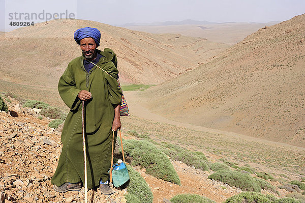 Ziegenhirte  älterer Mann mit Djellabah  Turban und Wasserflasche in den Bergen des Hohen Atlas  Marokko  Afrika