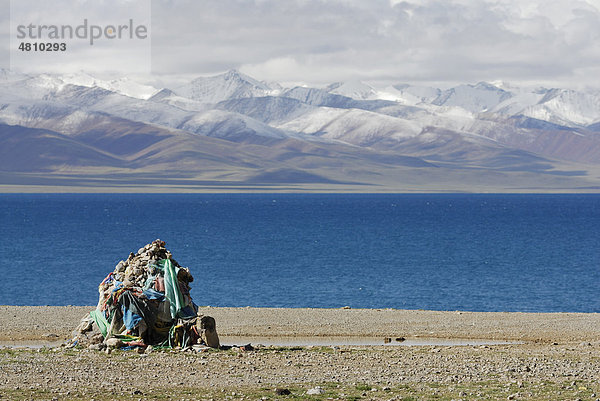 Steinhaufen mit Gebetsfahnen  schneebedeckte Gipfel des Nyenchen Thanglha am Namtso See  Himmelssee  Tibet  China  Asien