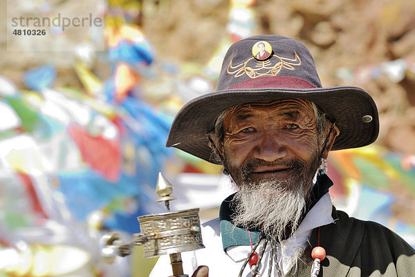 Tibetischer Pilger mit Gebetsmühle  dahinter Gebetsfahnen  Namtso See  Himmelssee  Tibet  China  Asien