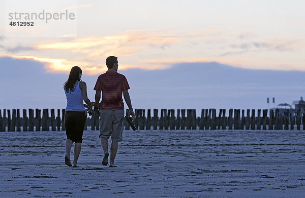 Junges Pärchen spaziert am Strand bei Sonnenuntergang  Zoutelande  Walcheren  Provinz Zeeland  Niederlande  Benelux  Europa