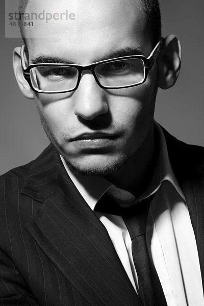 Portrait eines jungen Mannes mit Brille  Anzug  Hemd und Krawatte