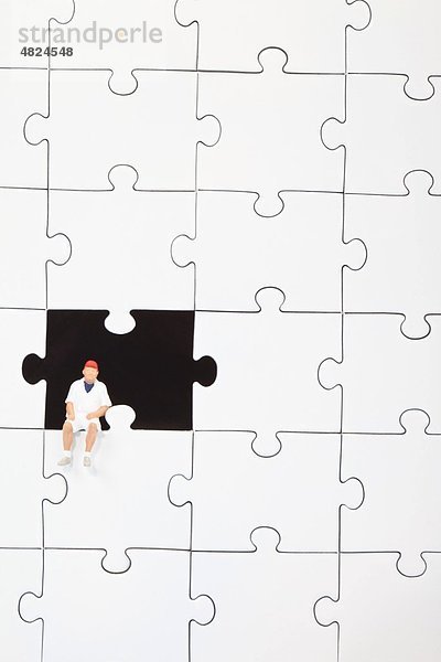 Männliche Figur auf Puzzleteil sitzend