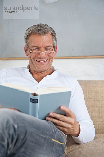 Reifer Mann liest Buch  lächelnd