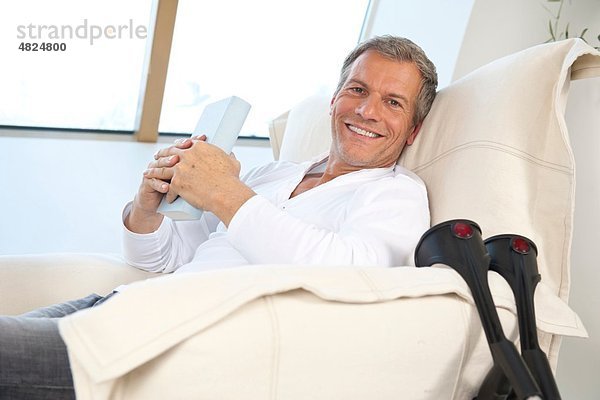 Erwachsener Mann auf Stuhl sitzend  lächelnd  Portrait