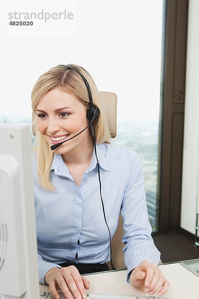 Geschäftsfrau mit Headset und Computer