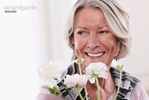 Seniorin mit Blumen  lächelnd