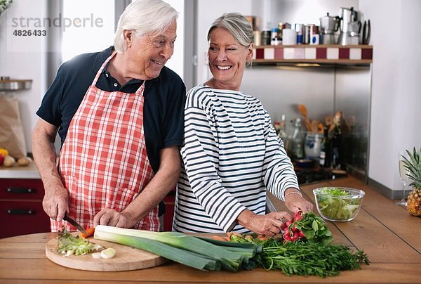 Deutschland  Wakendorf  Seniorenpaar beim Gemüseschneiden in der Küche