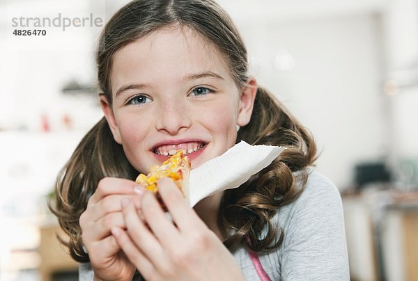 Ein Mädchen isst eine Scheibe Pizza.