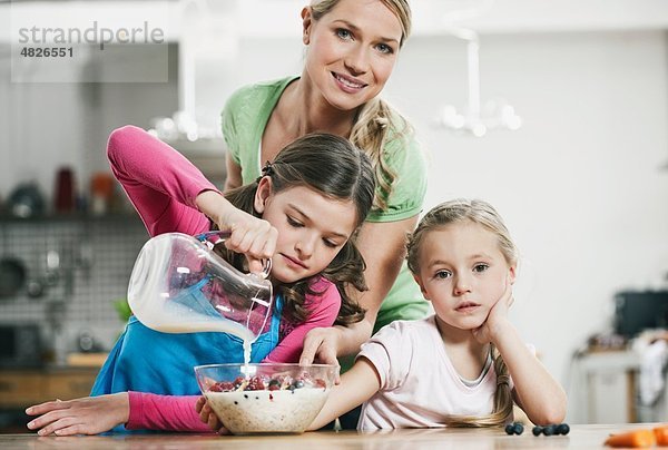 Deutschland    Mutter und Kinder bereiten Müsli zum Frühstück vor