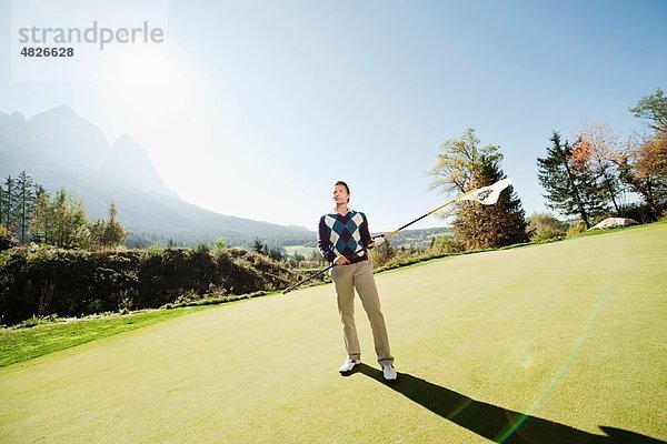 Italien  Kastelruth  Mittlerer Erwachsener Mann mit Golfflagge auf dem Golfplatz