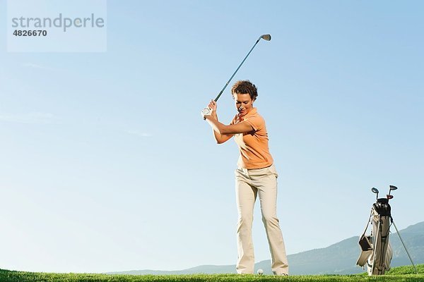 Italien  Kastelruth  Mittlere erwachsene Frau beim Golfen auf dem Golfplatz