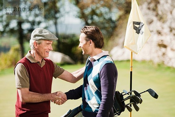 Italien  Kastelruth  Golfspieler beim Händeschütteln auf dem Golfplatz  lächeln