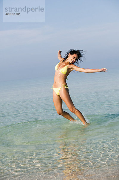 Junge Frau beim Springen im Meer