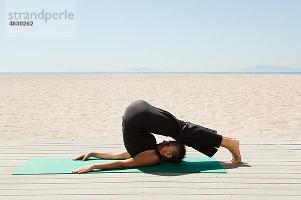 Senior Frau macht Yoga am Strand