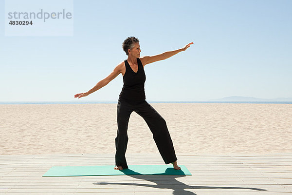 Seniorin beim Yoga am Strand