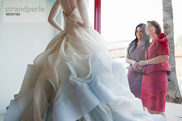 Mutter und Tochter beim Anblick des Hochzeitskleides im Schaufenster