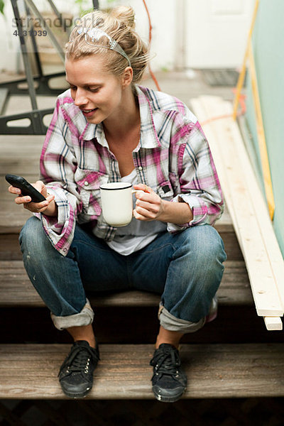 Frau auf der Treppe sitzend mit Smartphone