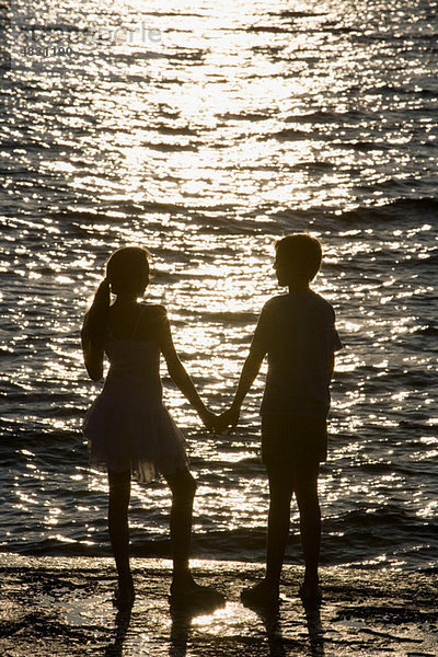Teenager-Paar beobachtet Sonnenuntergang über dem Meer
