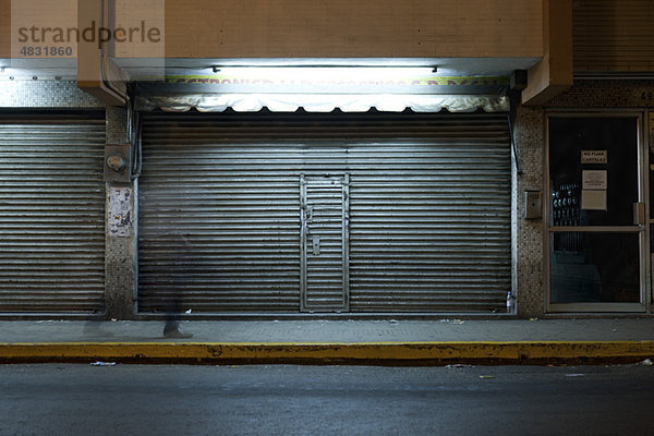 Ladenfront mit verriegelter Rolltür bei Nacht
