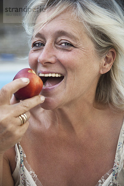 Reife Frau beißt in den Apfel