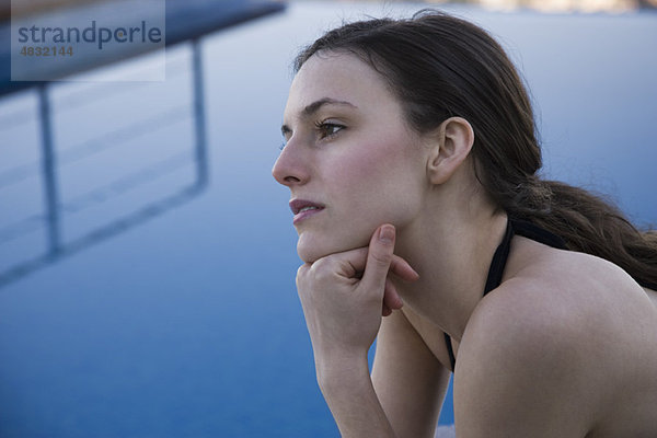 Frau am Pool  in Gedanken wegschauend