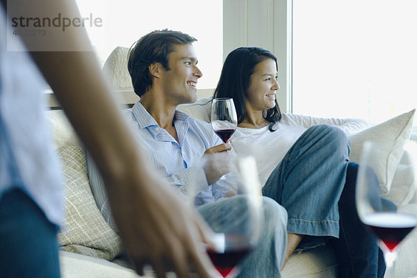 Paar genießt Rotwein auf dem Sofa