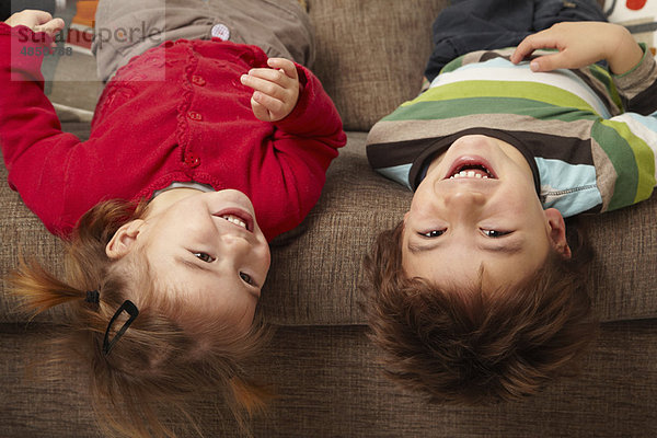 Junge und Mädchen lachend auf dem Sofa