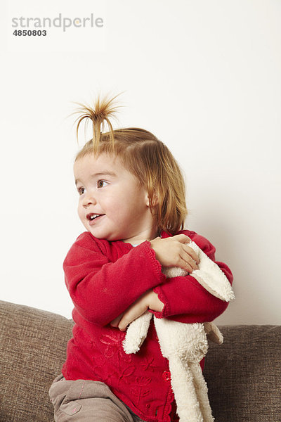 Junges Mädchen mit Teddybär auf Sofa