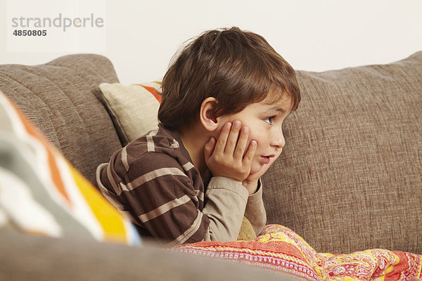 Junge auf dem Sofa  der auf das Fernsehen starrt.