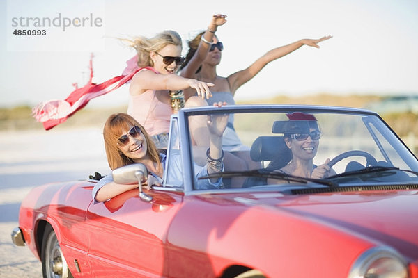 Mädchen mit rotem Schal fahren im Cabriolet