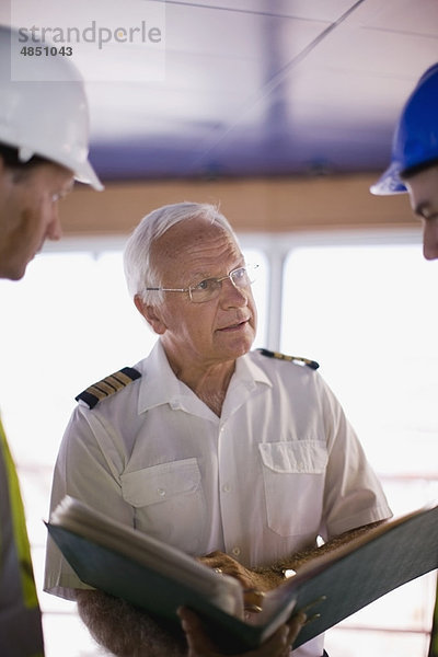 Kapitän eines Schiffes im Gespräch mit Arbeitern