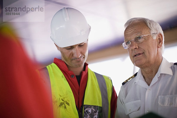 Kapitän eines Schiffes im Gespräch mit Arbeitern