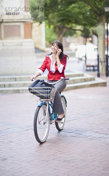 Frau auf dem Fahrrad beim Telefonieren