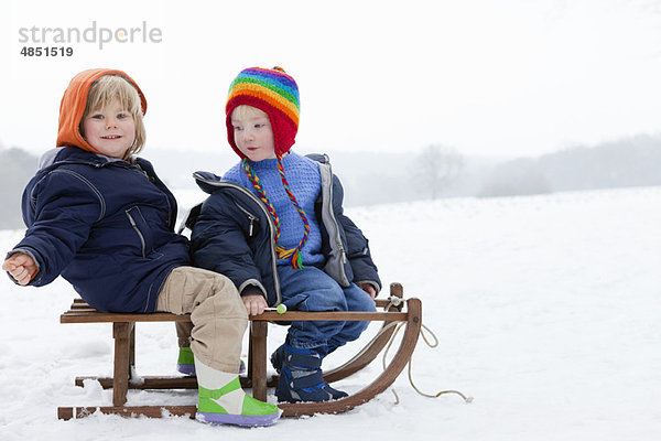 Zwei Jungen auf einem Schlitten im Schnee